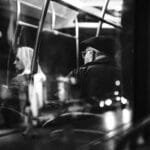 Pasażerowie w nocnym autobusie w czarno-białym ujęciu