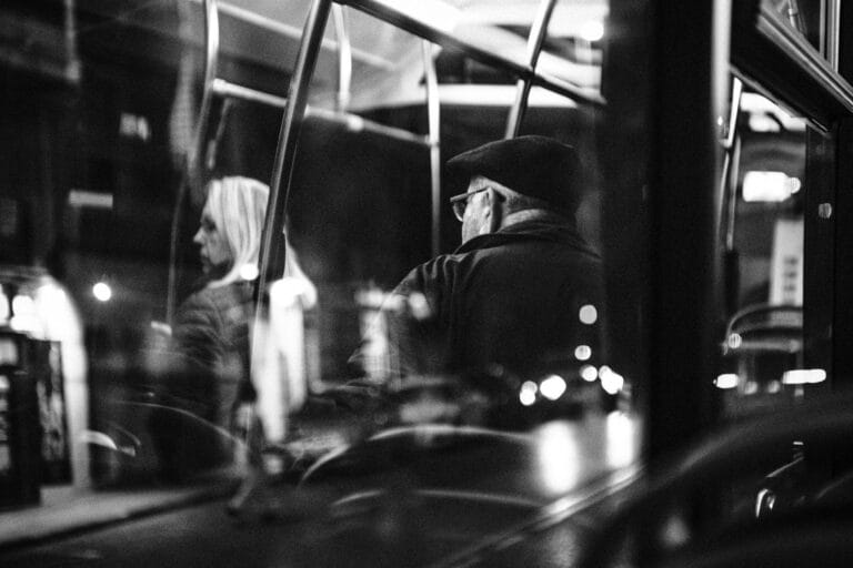 Pasażerowie w nocnym autobusie w czarno-białym ujęciu