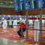 Terminal lotniska z tablicami lotów i kioskami odprawy